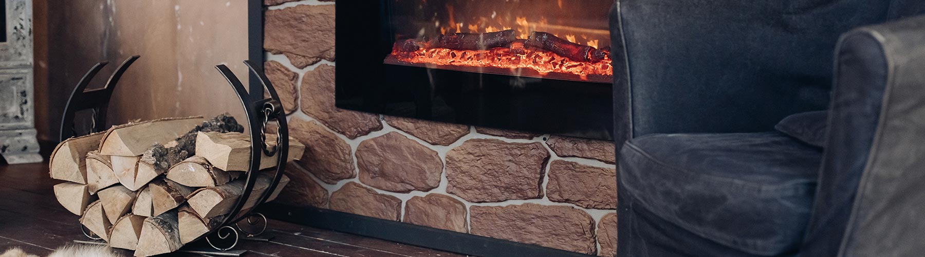 View over fireplace with burning logs, natural fur skin on the floor next to holder with logs