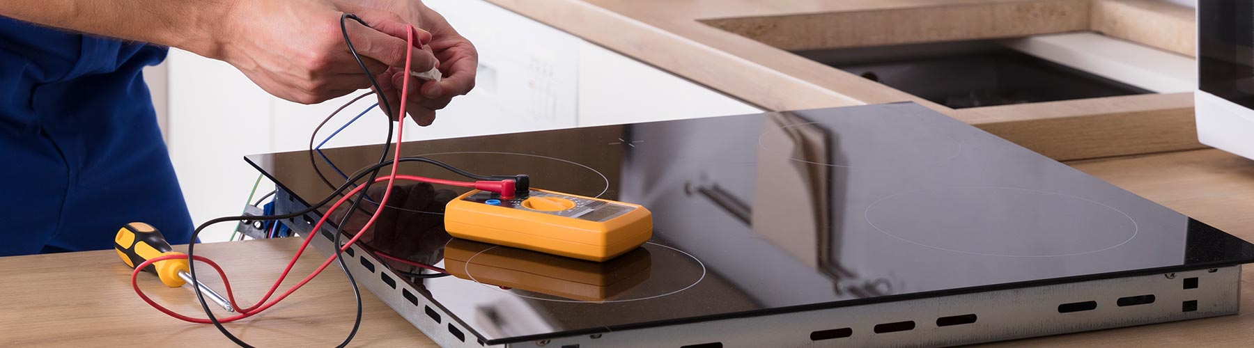 Technician Repairing Induction Stove In Kitchen