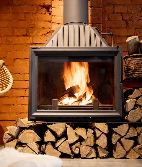 Cozy fireplace with firewood in the loft style home interior with brick wall