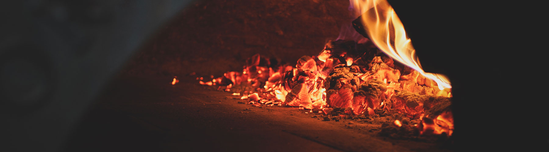 Toned dark photo of traditional oven for pizza with fire inside.